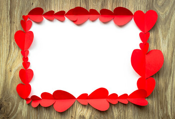 Valentine's Day background. Red paper hearts are lined with rectangle, on a wooden background with place for text. Bright colorful hearts for postcards. - 404883504