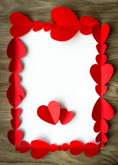 Valentine's Day background. Red paper hearts are lined with rectangle, on a wooden background with place for text with hearts. Bright colorful hearts for postcards. - 404883520