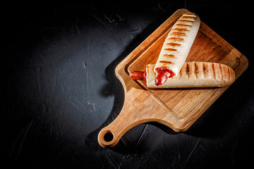 Two tasty grilled french hot dog with mustard and ketchup on dark background