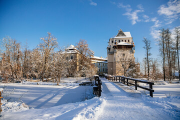 Fototapeta na wymiar Medieval renaissance water castle with half-timbered tower with snow in winter sunny day, Historic Romantic chateau Blatna near Strakonice in southern Bohemia, Czech Republic