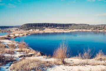 Fototapeta na wymiar Lake in the middle of the forest with blue water on a sunny early spring day