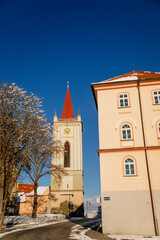 Baroque bell tower called Blatenska vez in winter, Narrow picturesque street, renaissance historical buildings with snow, Blatna near Strakonice in southern Bohemia, Czech Republic