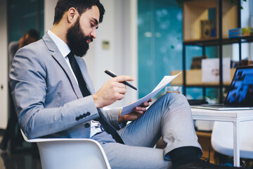 Serious entrepreneur reading documents in modern workspace