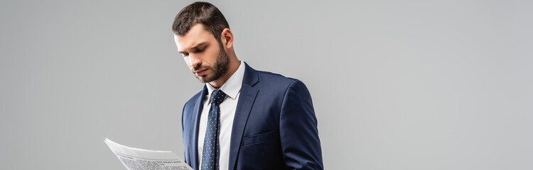 thoughtful businessman reading newspaper isolated on grey, banner