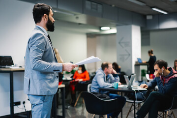 Serious businessman standing with documents in modern office lounge room