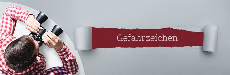 Gefahrzeichen. Mann (Anwalt) bei Beobachtung mit Fernglas. Fokus auf Text/Wort in einem Papier Riss.