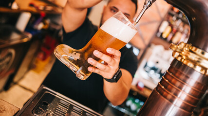 Bartender draft beer in tap in beer glass boot.