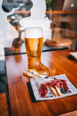 Beer glass boot with delicious spanish iberian ham snacks on a wooden table