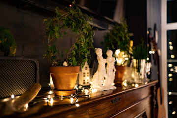 white figurines of children singing Christmas songs on the piano. New Year's decoration of the house. garlands in the interior. Low light. Selective focus.