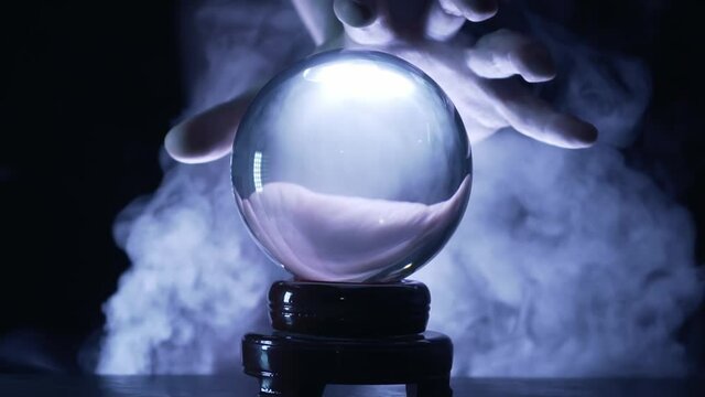 Hand of magician or fortuneteller above glass ball. Oracle is predicting the future.