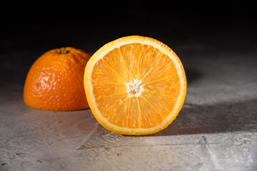 Orange cut in half on gray and black background. Close up, copy space