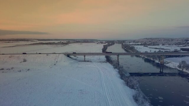 Winter. Sunset. bridge across the Dnieper. Belarus. Aerial photos from a drone of a river against the background of a forest and a bridge, cars moving along it. Rural area. The sunset or sunrise , a b