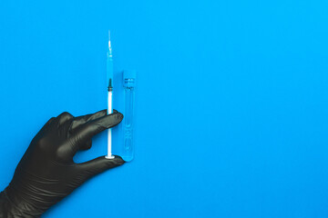 Injection. Doctor hand in medical glove hold syringe with needle for protection flu virus and coronavirus. Covid vaccine isolated on blue. Nurse or doctor. Liquid drug or narcotic.