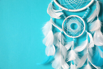 Beautiful dream catcher hanging on light blue background, closeup. Space for text