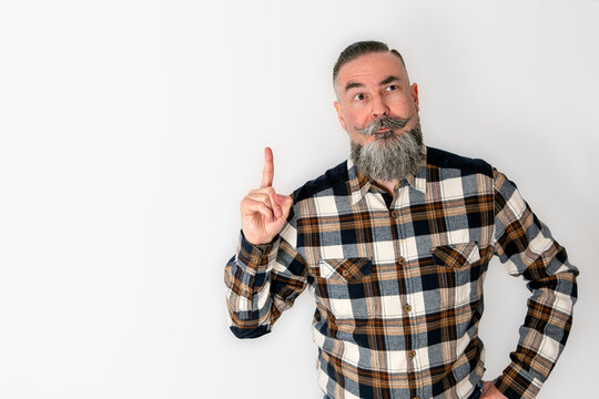man with big beard and mustache in retro style, plaid shirt with peculiar appearance and funny expression, raising the index finger of the hand with a funny and original gesture