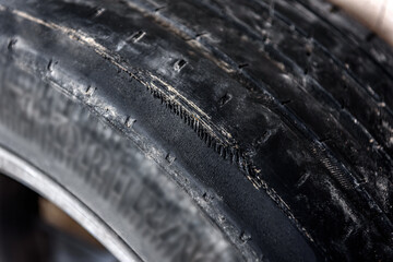 A tire with worn rubber tread to the cord. A worn wheel. 