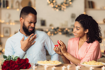 Black woman making proposal with ring to her confused boyfriend