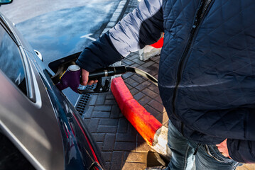 Hand refilling the car with fuel at the refuel station.