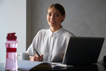 Woman using laptop and smiling while working at home