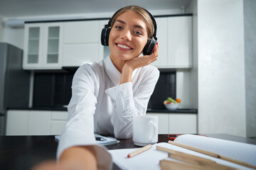 Smiling woman in headphones having video call on laptop