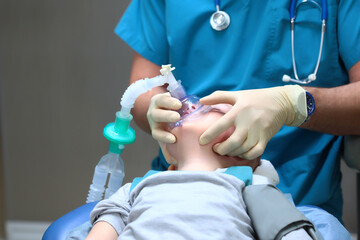 Preparing a young boy for dental surgery. General anesthesia. Treatment of multiple caries of baby...