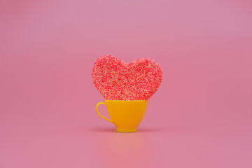 Heart in a toy cup on pink background. Love, wedding and Valentine's day celebration concept. Copy space