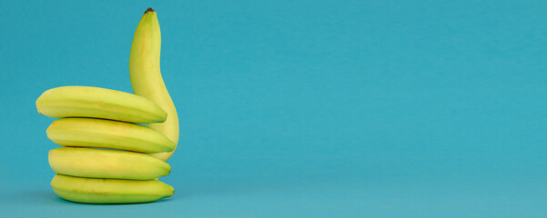 Like gesture on blue background of bananas. Banana showing thumb up