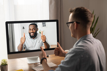 Video call, video meeting. A young man is discussing some business tasks with a young African man...