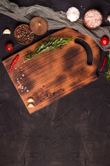 Wooden cutting board on a black table. Top view of empty kitchen trendy rustic wooden tray with copy space.