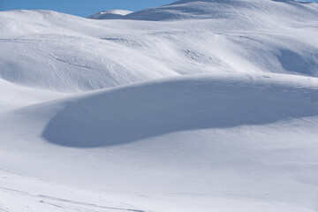 un bel paesaggio di montagna innevato, delle dune di neve in luce-ombra sembrano quasi un deserto.