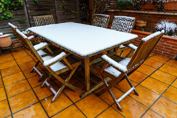 Snow-covered garden furniture in cold winter day.
