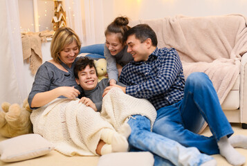 portrait of a family sitting on a sofa at home, four people having fun together