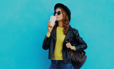 Portrait of beautiful young woman wearing a black round hat, black jacket on a blue background