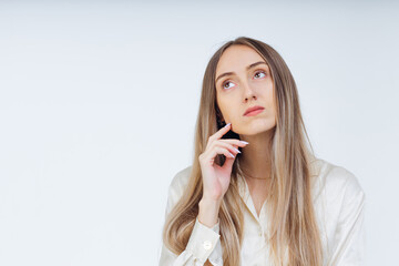 Pensive young woman looks to the side, feeling doubt isolated on white studio wall, uncertain face thinks about question.
