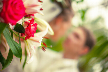 Obraz na płótnie Canvas Beautiful bouquet of flowers on the background of a blurred silhouette of a loving couple of bride and groom.