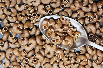 Heap of spelt pasta on a spoon top view