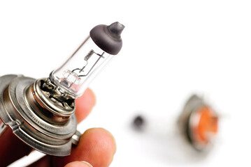 A car headlight bulb in hand on a white background.	
