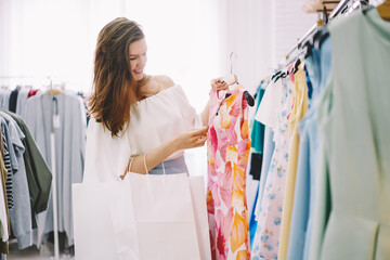 Joyful woman choosing clothes in shop