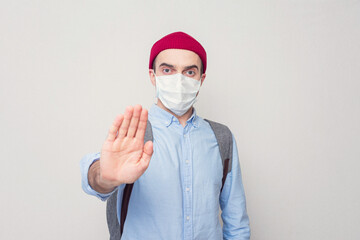 Man in a medical mask shows a stop sign, portrait