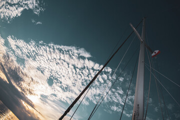 Sailing mast and clouds on blue sunset sky.