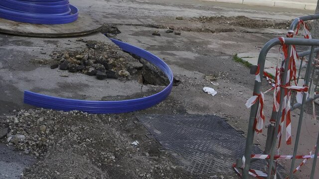 digging a restricted section for buried corrugated plastic conduits to run fiber optic cables for telecommunications distribution network.