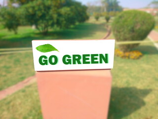 view of signboard with go green text in unfocused blur garden background