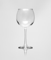 Empty wine glass on a white grainy background, reflection and shadow effect