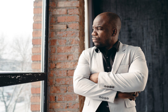 Fashion Black Man Looks Out The Window In A Photo Studio. Fashionable Portrait Of An African American Man. Business Style