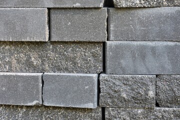 Stack of new grey bricks, selective focus. Construction materials building. Gray cement solid bricks for building. Abstract grunge background 