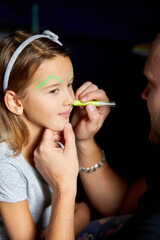 Daughter and father paint a face, having fun, leisure together at home