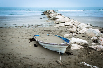Una piccola barca di legno abbandonata e sepolta dalla sabbia sulla spiaggia del Lido di Venezia