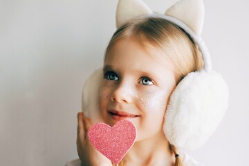 Cute blue-eyed little girl holding pink heart for valentines day. Lovely smiling child with heart. Hipster. Love. - 404924798