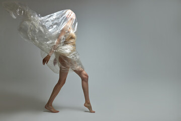 full-length portrait of slim half-naked woman in bodysuit posing with transparent plastic bag isolated in studio, helping spread environment cleaning nature from pollution awareness concept