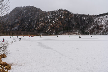 Eisstock Spieler und Eisläufer auf dem zugefrorenen Almsee in Oberösterreich